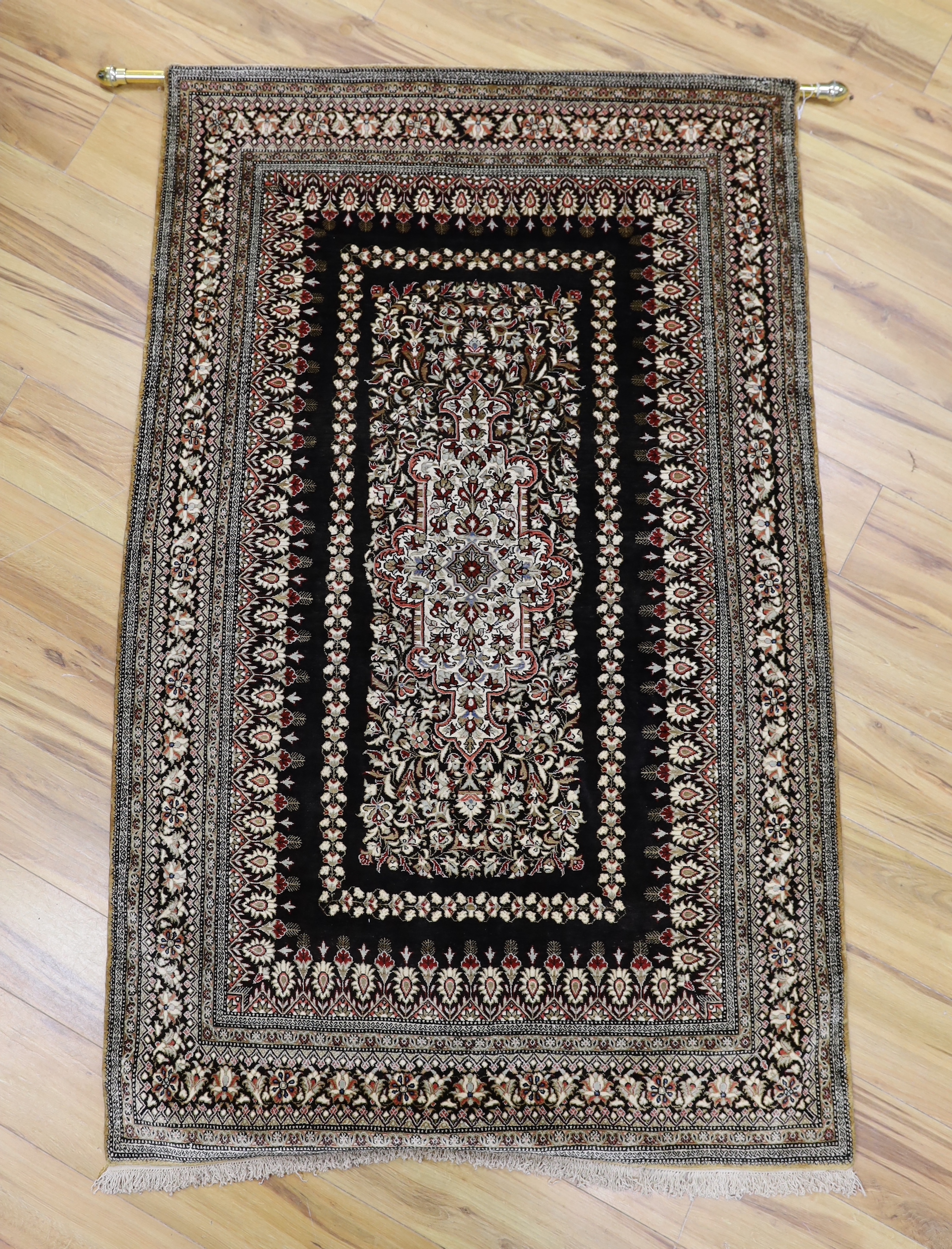 A Persian Qum silk rug, mounted as a wall hanging on a brass rod, 168 x 105cm